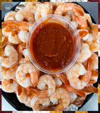 Platter of shrimp with a small container of sauce on a black plate.